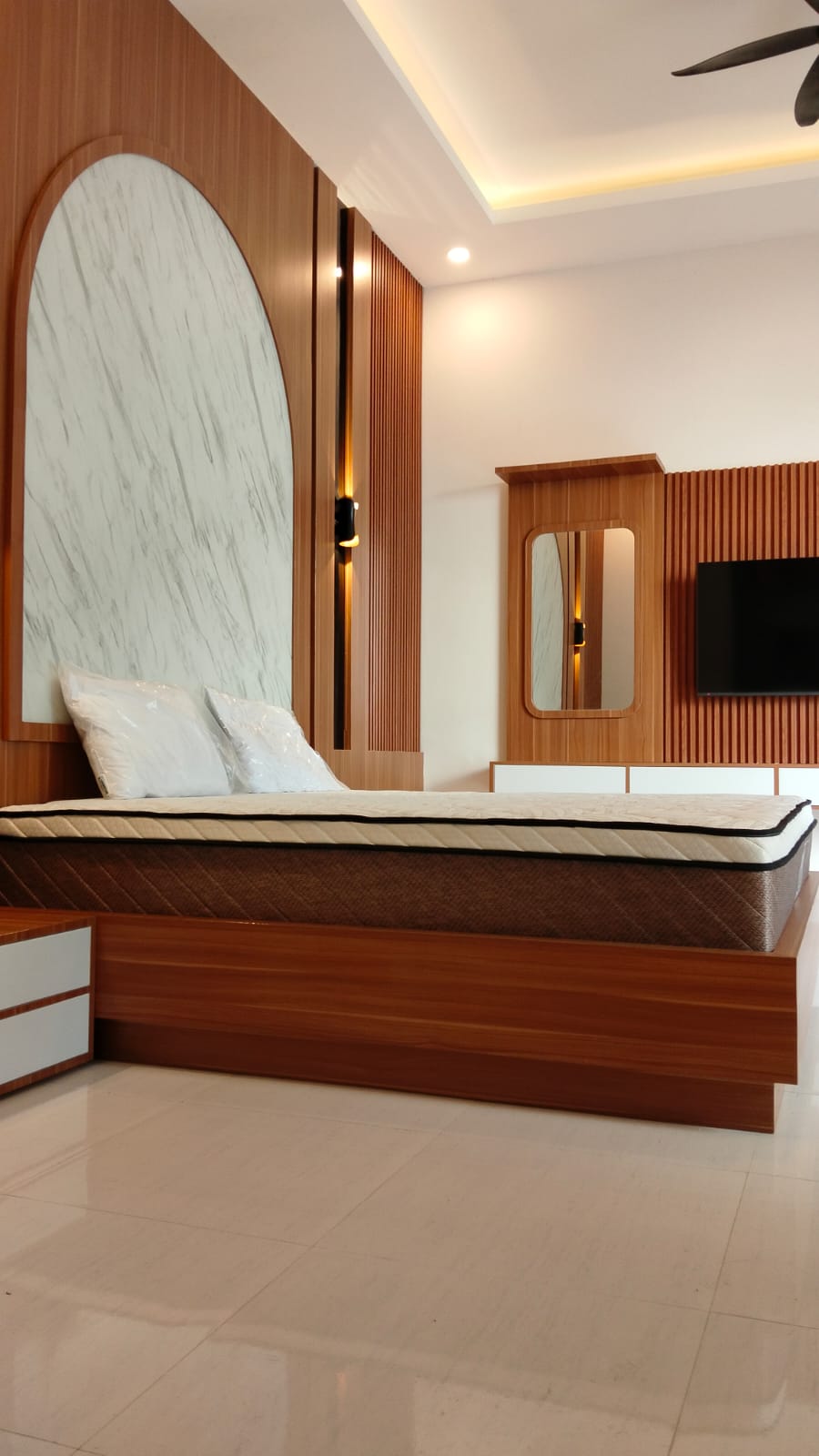 Primary bedroom with warm timber details and soft lighting